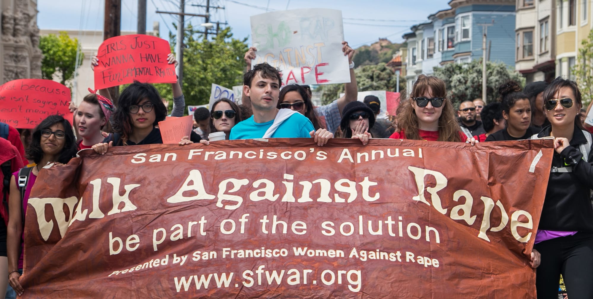 Students and protesters hold signs and banners during a Walk Against Rape march, Saturday, April 26, 2014. Participants marched for more than three miles to support victims and families of abused women. Photo by Elisa Parrino/The Guardsman
