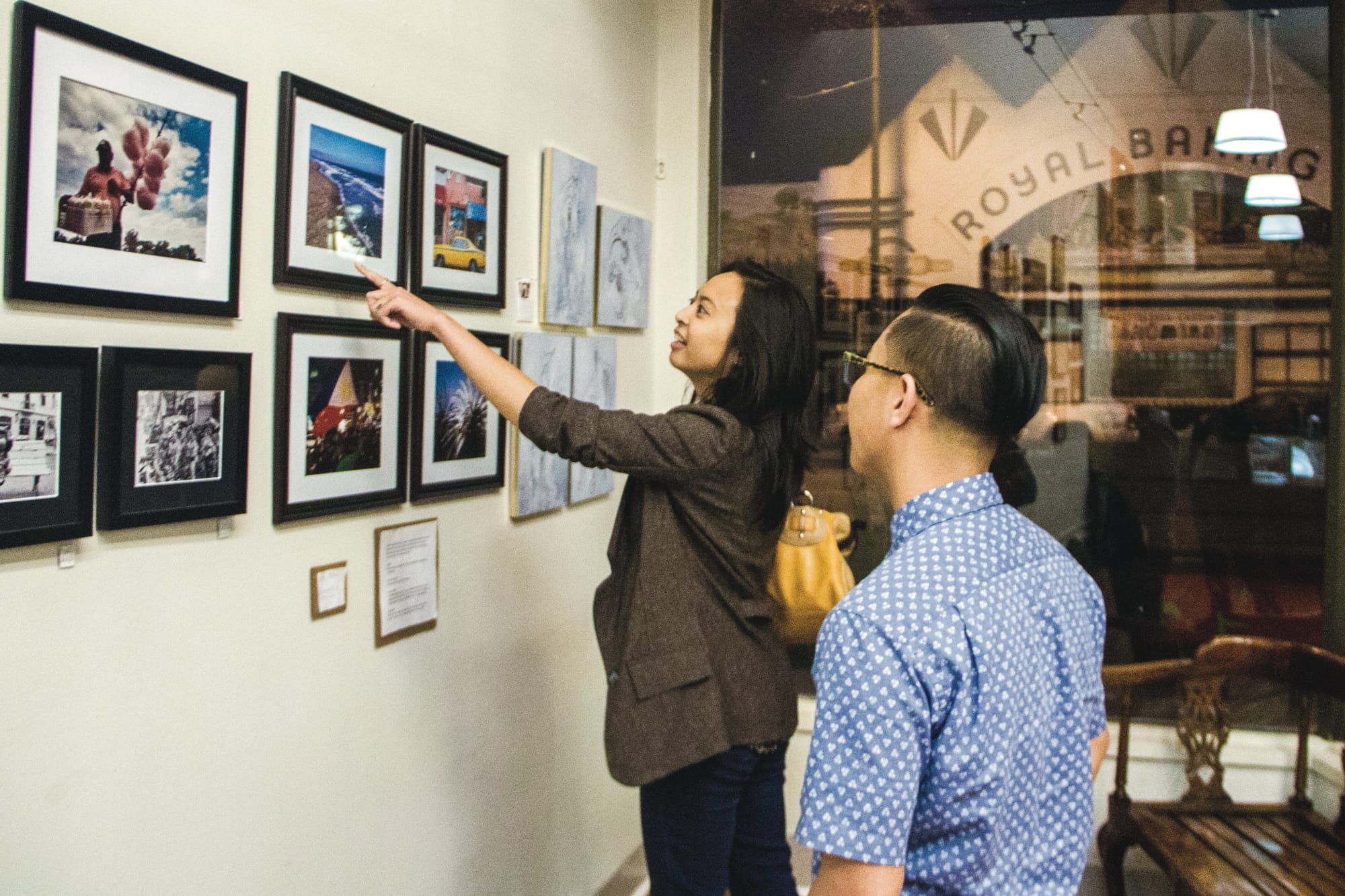 Shane Menez (right), City College journalism student and curator of the Mission&Vision art show, and Laurenmarie Reyes, event manager for the Mediate art group, take time to enjoy the work in the exhibit, Friday, Sept. 12 at Mama' Art Cafe in the Excelsior. (Photo by Beatriz Escobar/ Contributor)