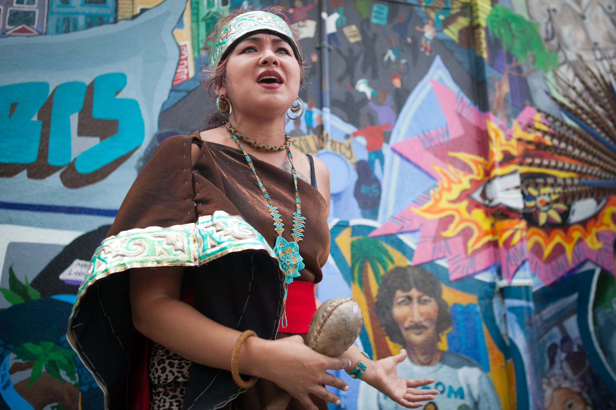 Spiritual traditional dancer Sandra Sandoval of Xiuhcoatl Danza Azteca speaks to the crowd during the celebration of the mural project, at the corner of 24th and Folsom streets on Saturday, Aug. 8, 2015. (Photo by Ekevara Kitpowsong/TheGuardsman)