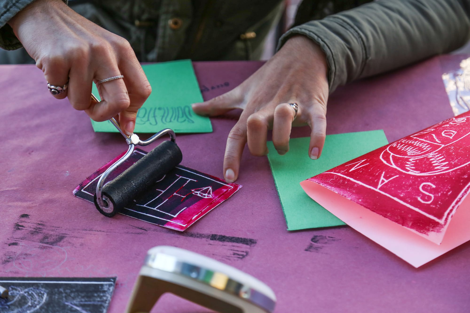 A woman stops by the sidewalk art booth in downtown San Francisco to make a relief print greeting card.