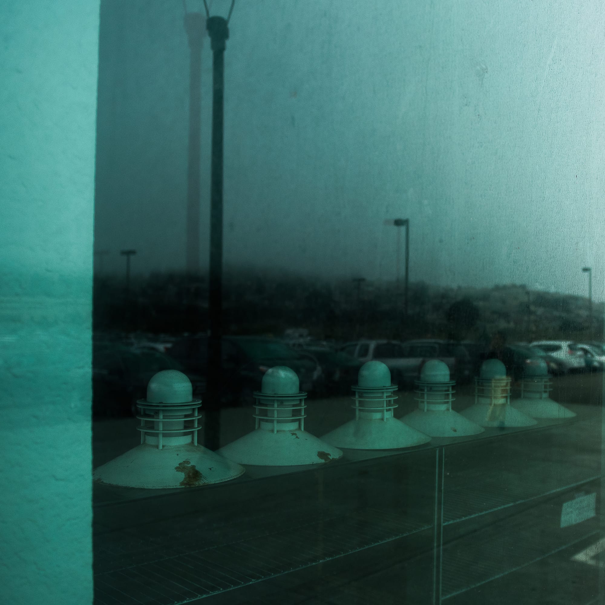Reflection of students over disused lights visible in reflective window of the closed Chasing Lions cafe. August 28, 2017. Photo by Otto Pippenger.